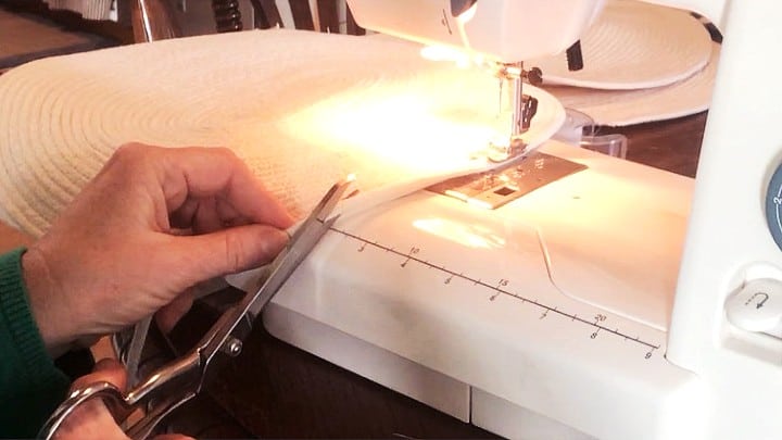 Picture of sewing placemat on machine and cutting end of rope at an angle to join new piece of rope.